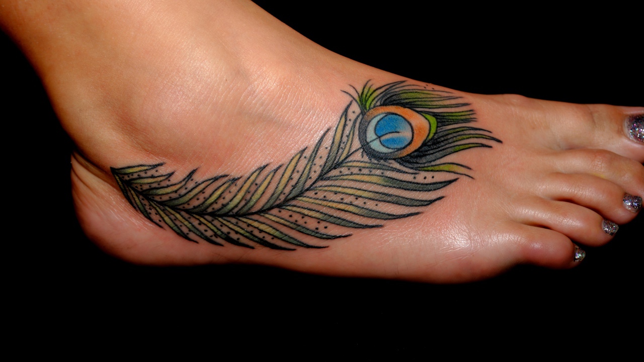 Татуировка перо павлина на ноге на черном фоне