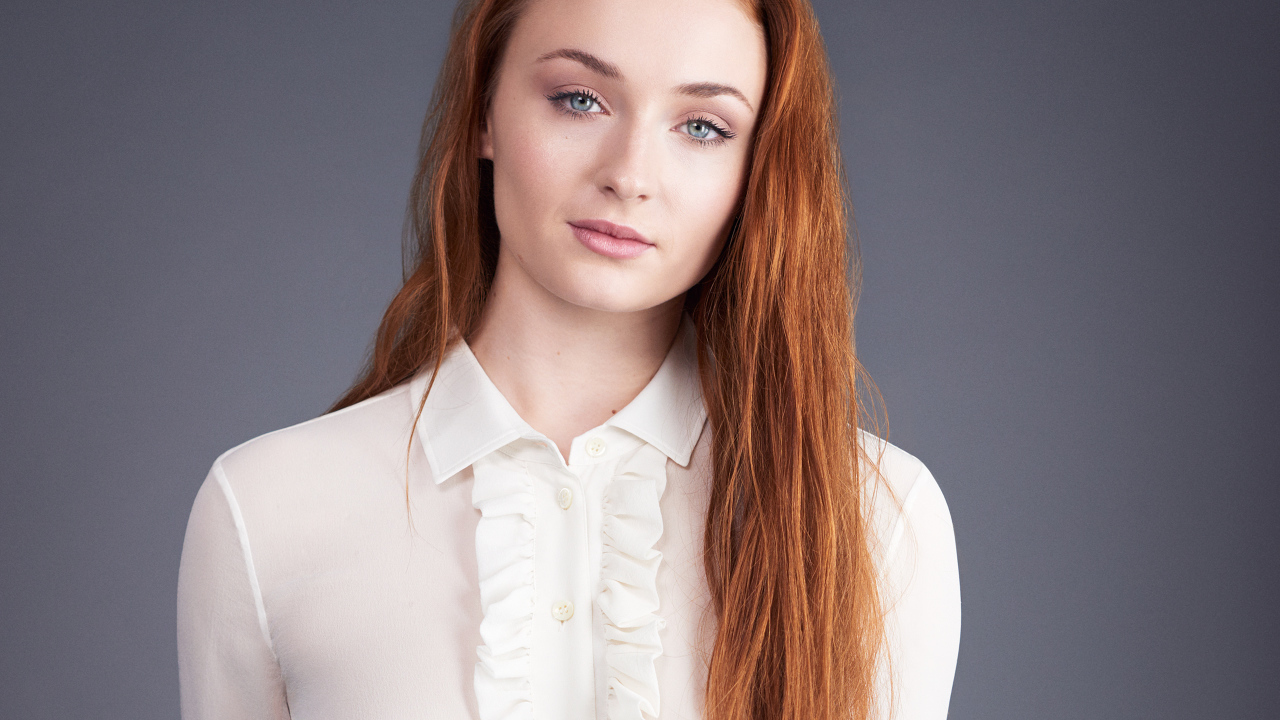 Рыжеволосая голубоглазая актриса Софи Тёрнер на сером фоне