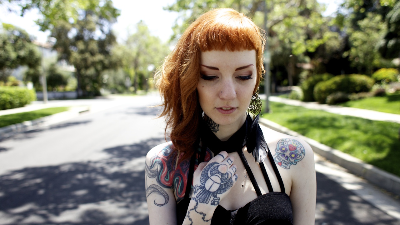 Рыжеволосая девушка неформалка с татуировками на теле