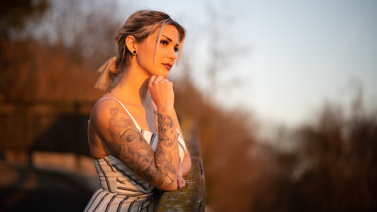 Молодая девушка с татуировкой на руке в лучах солнца