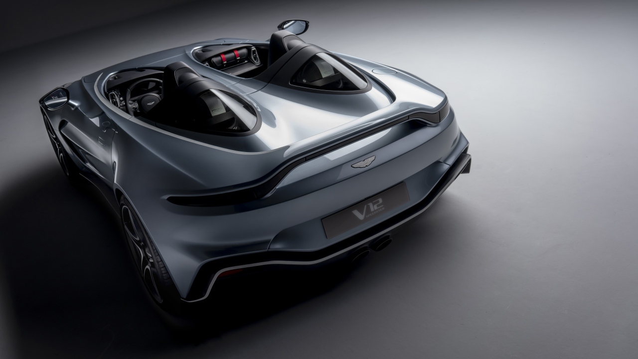 Серебристый автомобиль Aston Martin V12 Speedster 2020 года на сером фоне вид сзади