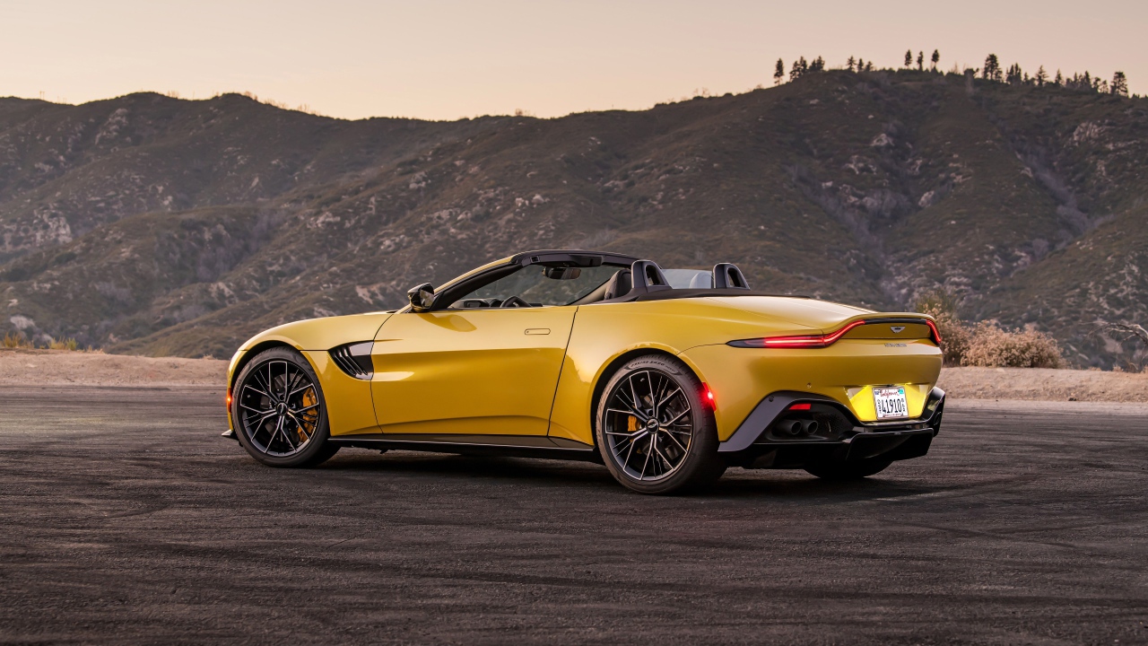 Желтый автомобиль  Aston Martin Vantage Roadster, 2021 года на фоне гор 