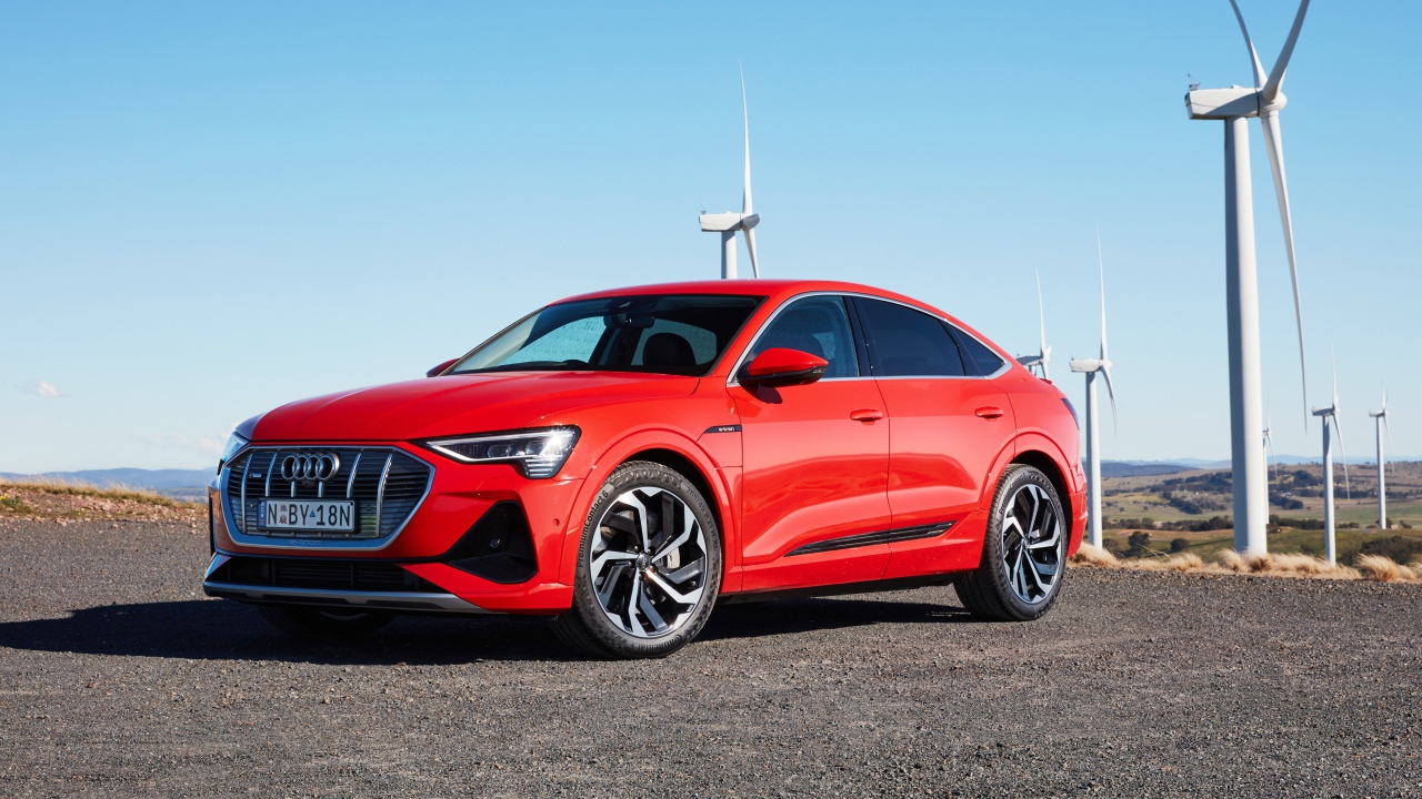 Красный автомобиль Audi E-Tron 50 Quattro Sportback S Line 2020 на фоне ветряных турбин