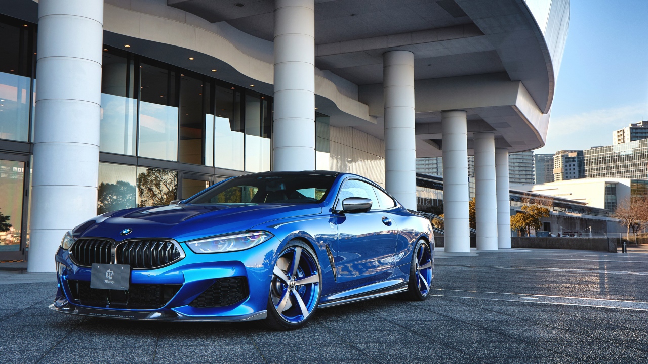 Синий автомобиль BMW M850i XDrive Coupe 2020 года у здания 