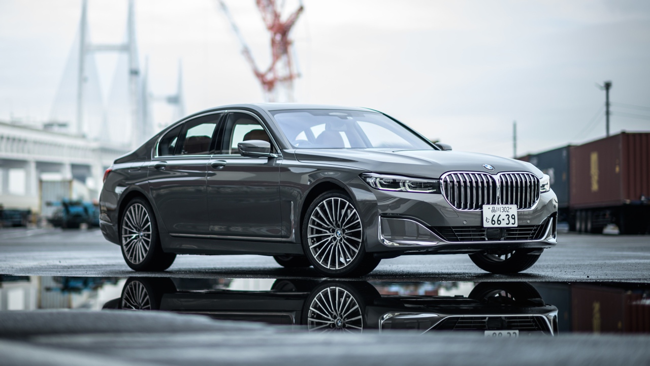 Серебристый автомобиль BMW 745e на мокром асфальте 