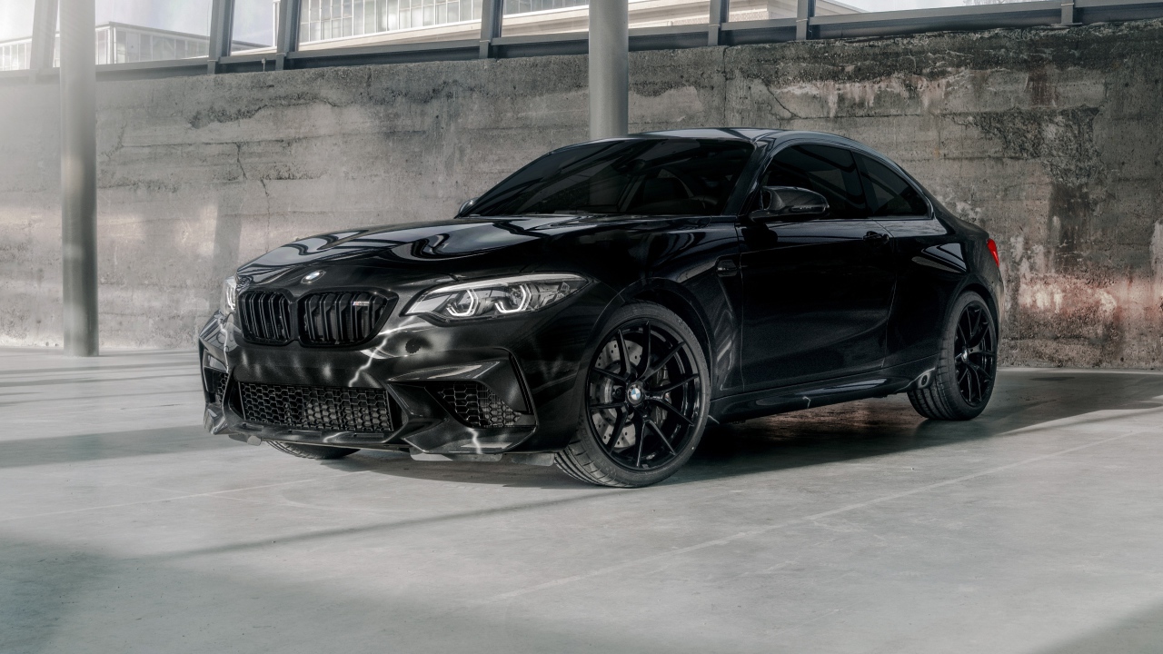 Черный автомобиль  BMW M2, 2020 года у бетонной стены