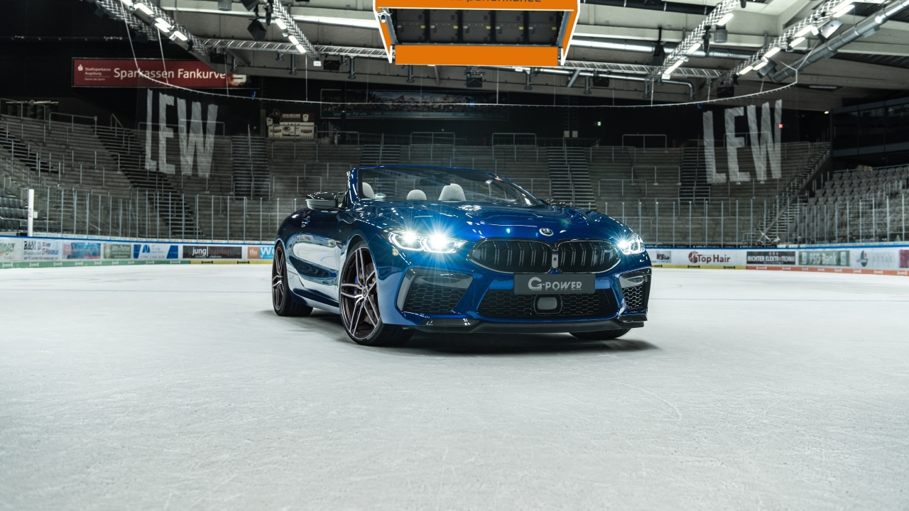 Кабриолет BMW M8,  2020 года с включенными фарами на стадионе 