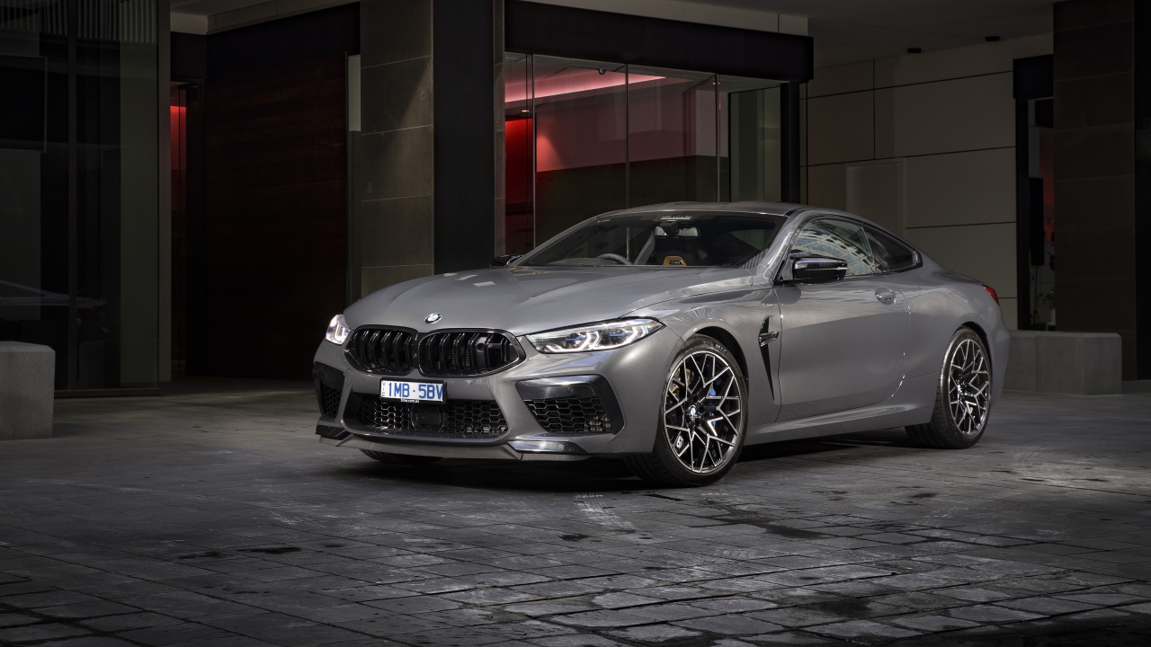 Серебристый автомобиль BMW M8 Competition Coupe 2020 года у здания 