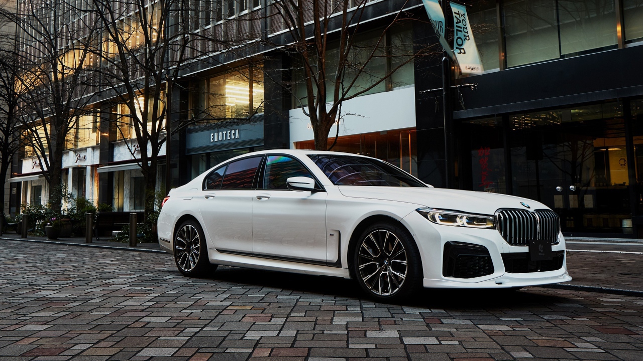 Белый автомобиль  BMW 740i M Sport 2020 года у кафе