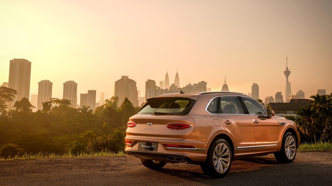 Автомобиль Bentley Bentayga V8 2020 года вид сзади на фоне города 