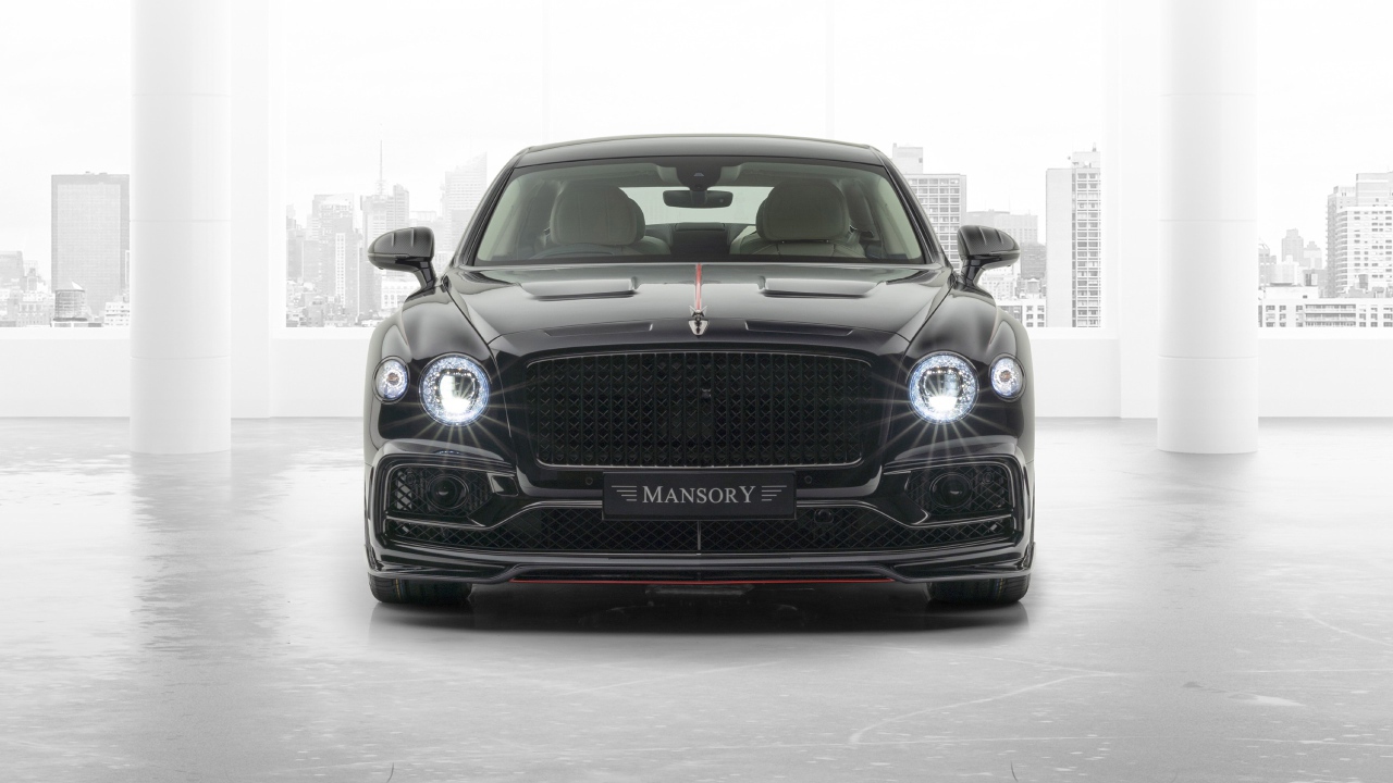 Черный автомобиль Mansory Bentley Flying Spur 2020 года с включенными фарами 