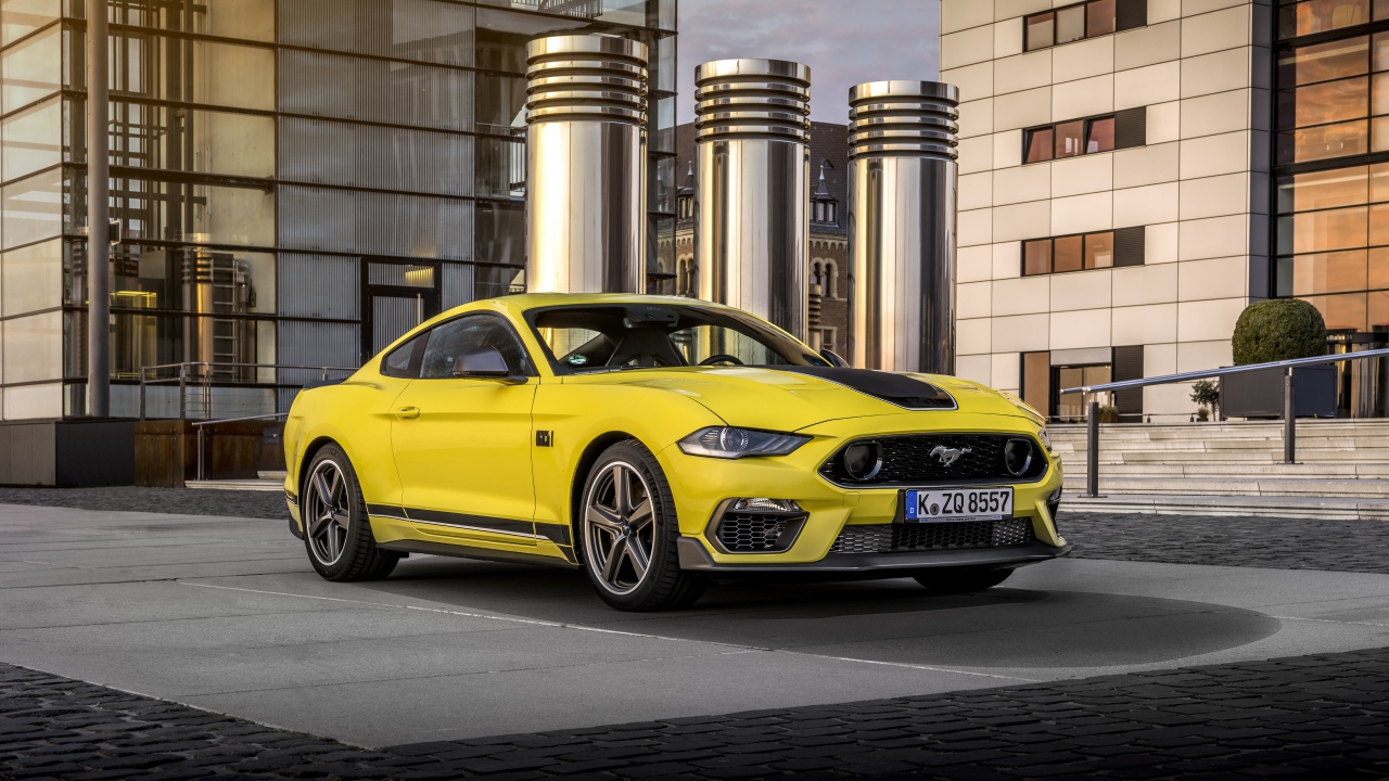 Быстрый желтый автомобиль Ford Mustang Mach 1 2021 года у здания 