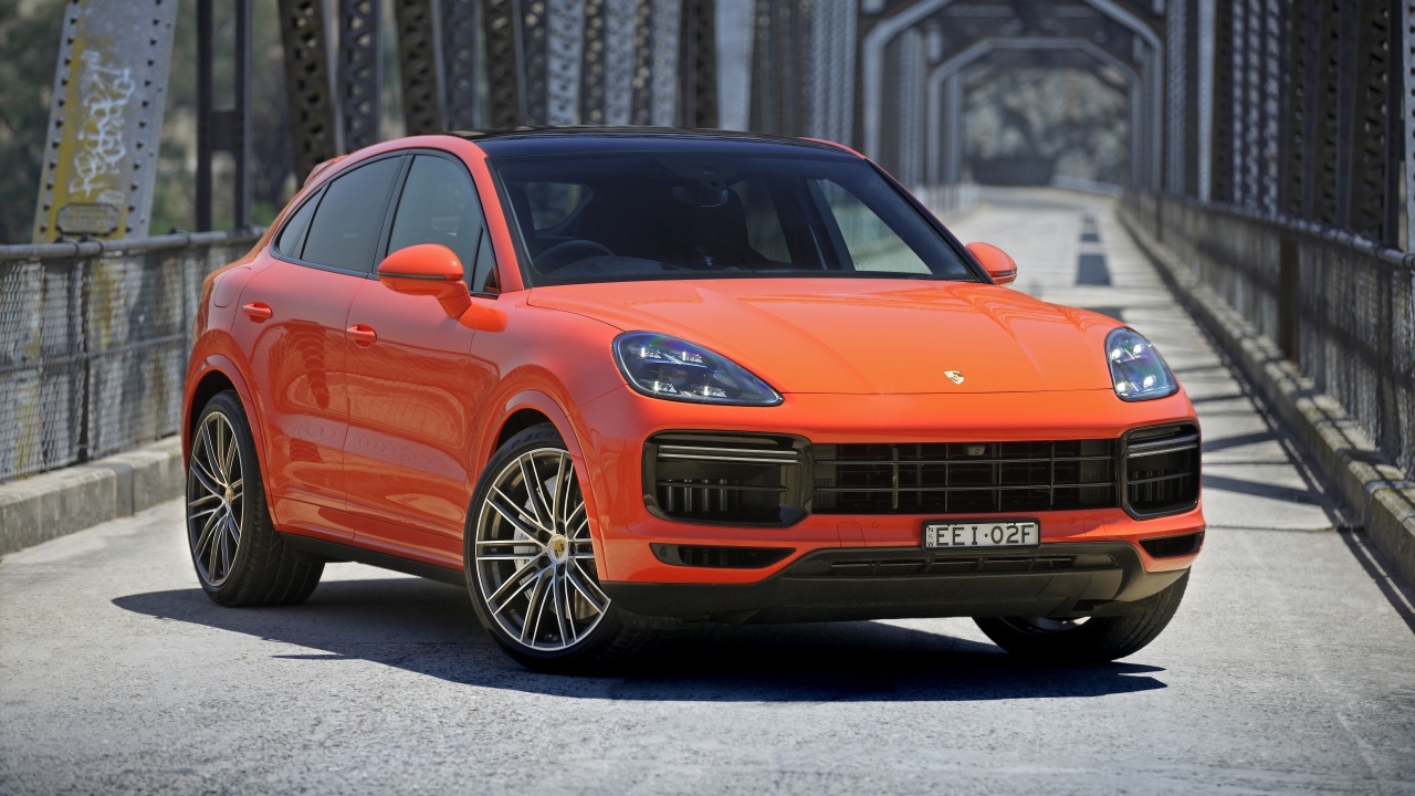 Оранжевый внедорожник Porsche Cayenne Turbo Coupe 2019 года на мосту