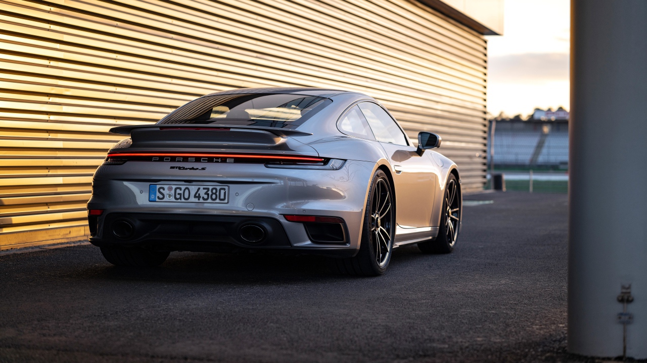 Серебристый автомобиль Porsche 911 Turbo S 2020 года у гаража