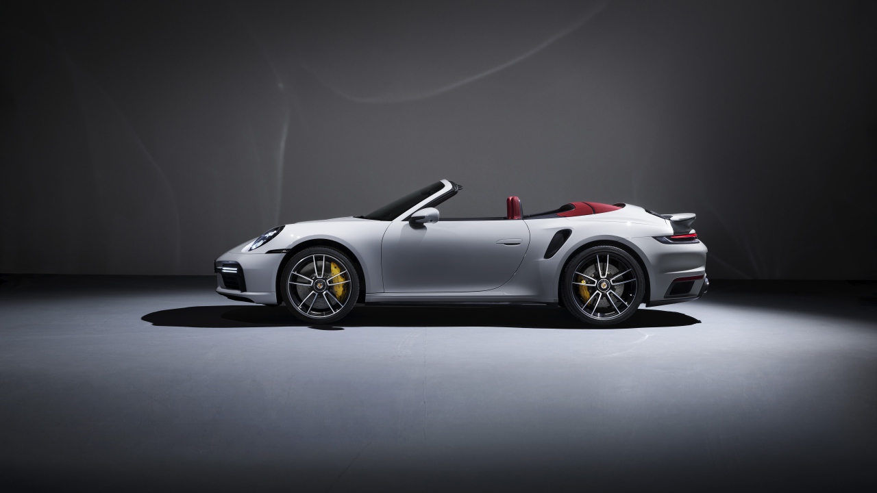 Белый автомобиль Porsche 911 Turbo S Cabriolet 2020 года на сером фоне