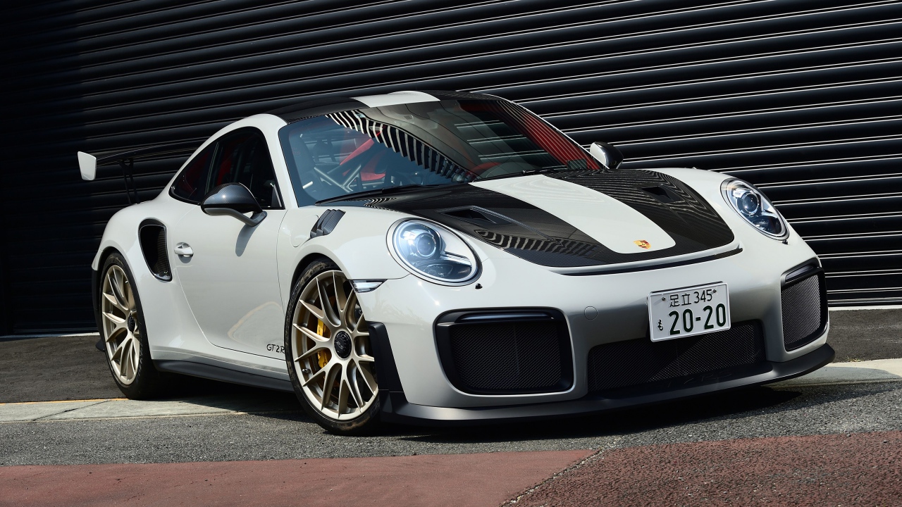 Белый автомобиль Porsche 911 GT2 RS  у черной стены