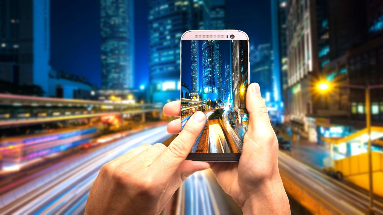 Мужчина делает фото ночного города на смартфон 