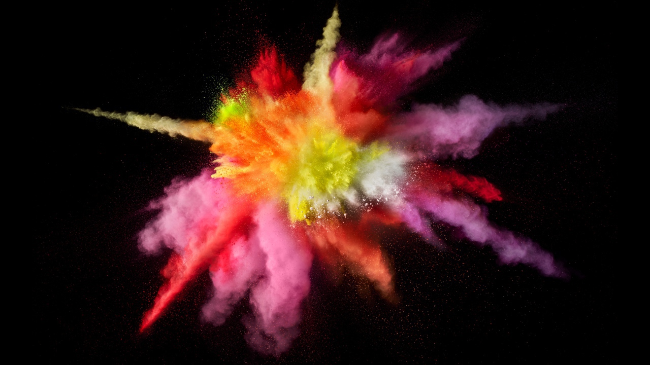 Multicolored explosion of dry paint on a black background
