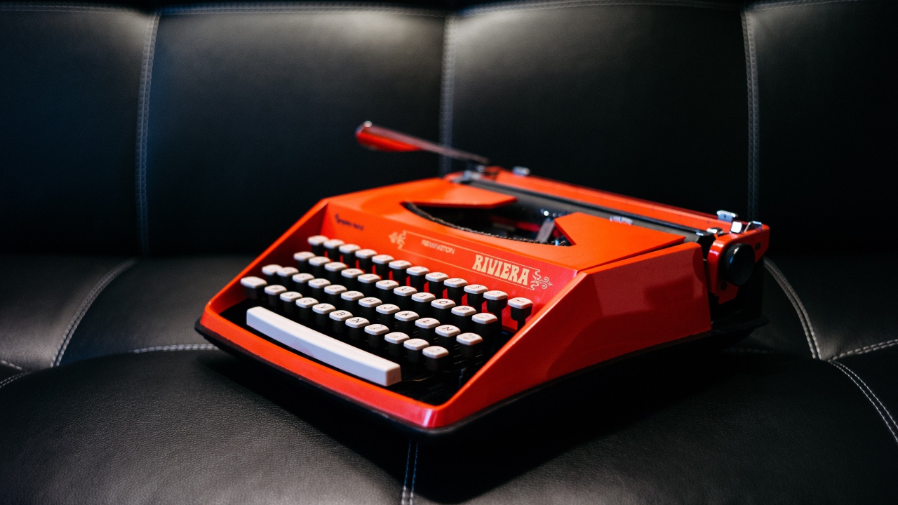 Старая красная печатная машинка на черном диване