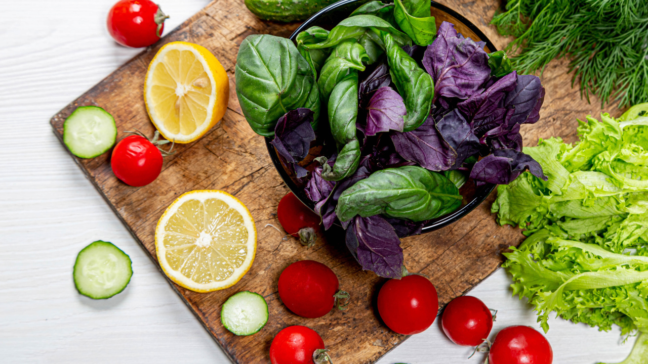 Базилик на столе с зеленью, помидорами и лимоном