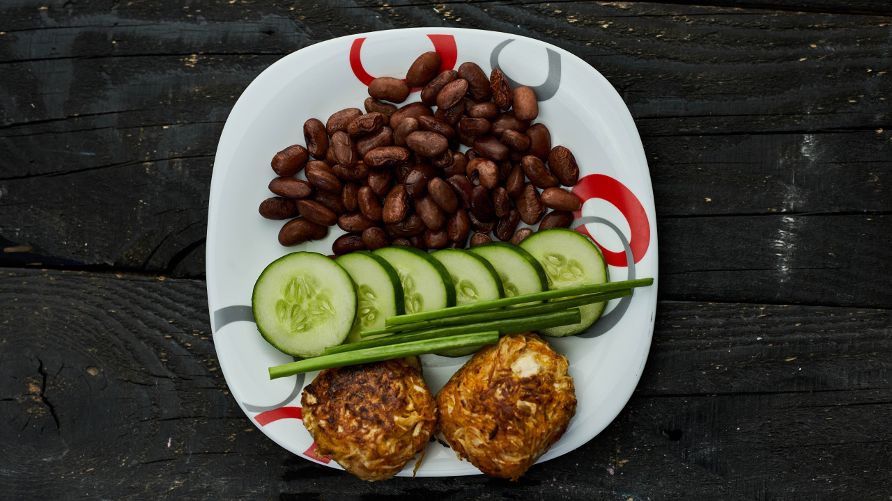 Фасоль на тарелке с оладьями и огурцами 