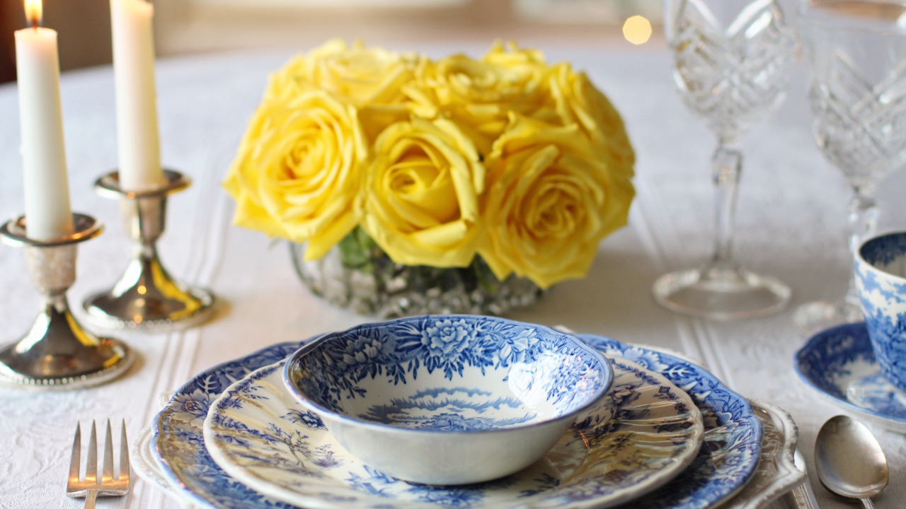 Красивая посуда на столе с букетом роз и свечами