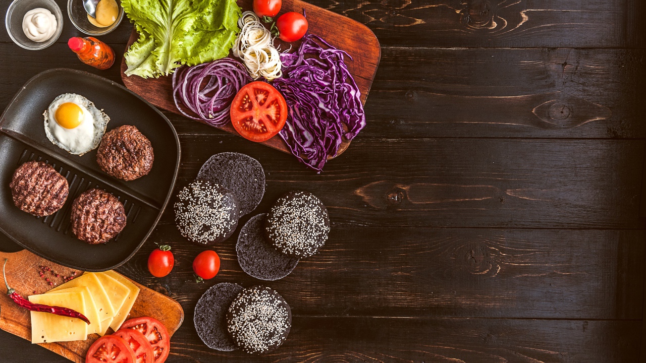 Повар готовит гамбургеры на деревянном столе