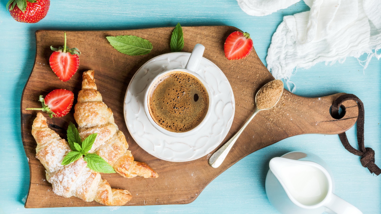 Чашка кофе на доске с клубникой и круассанами