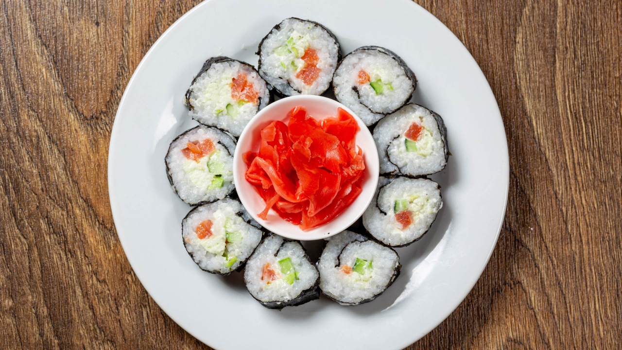 Вкусные суши на большой белой тарелке с имбирем
