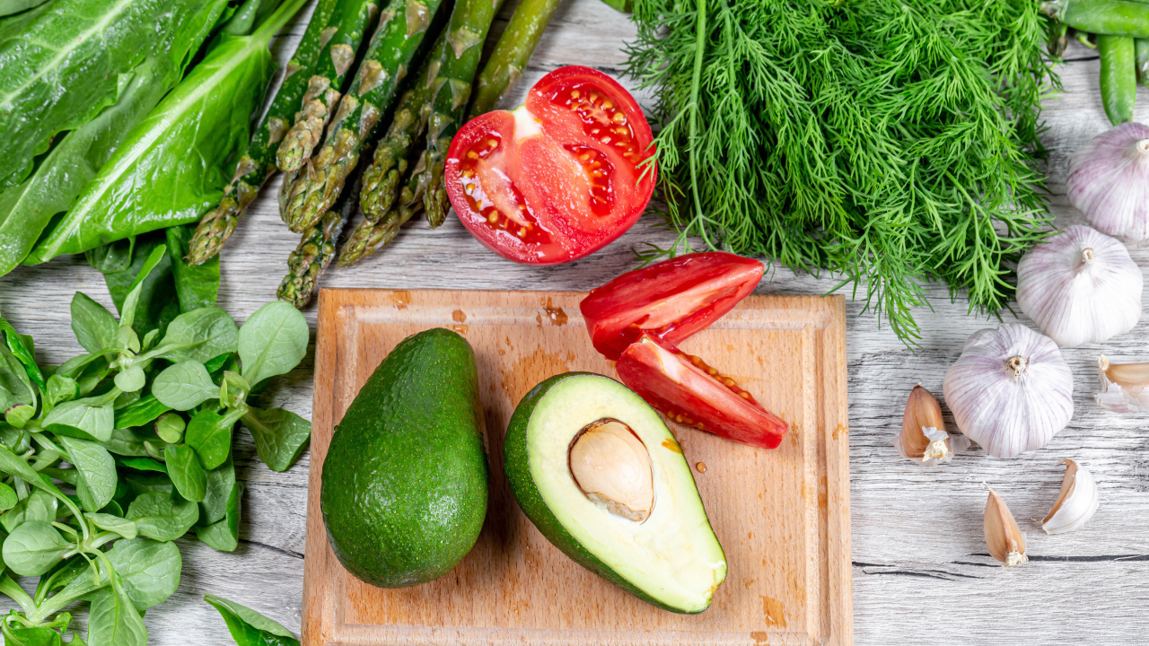 Свежая зелень на столе с авокадо, помидором и чесноком