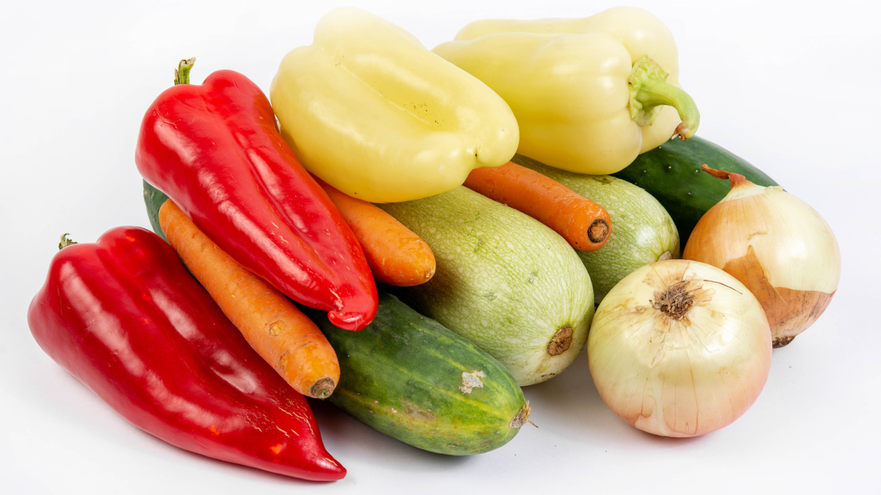 Свежие кабачки, огурцы, морковь, перец и лук на белом фоне