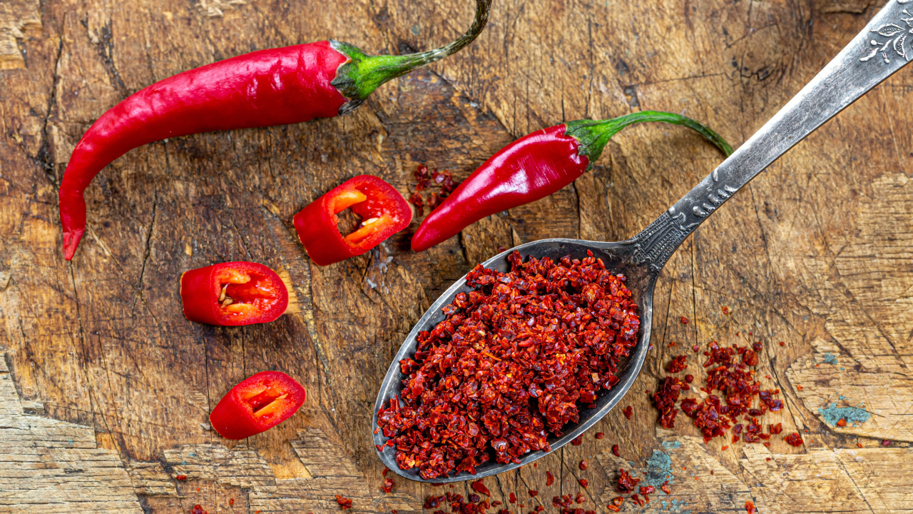 Молотый красный перец на ложке на столе 