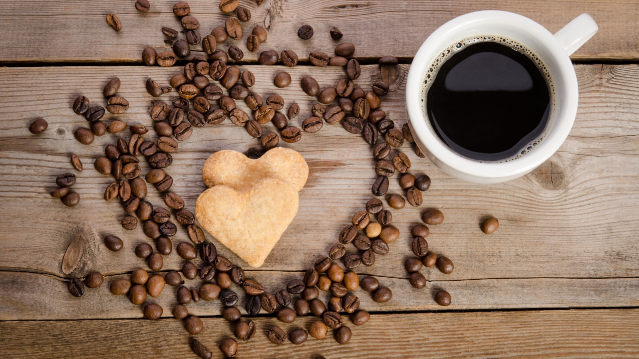 Печенье в форме сердца на столе с зернами и чашкой кофе 