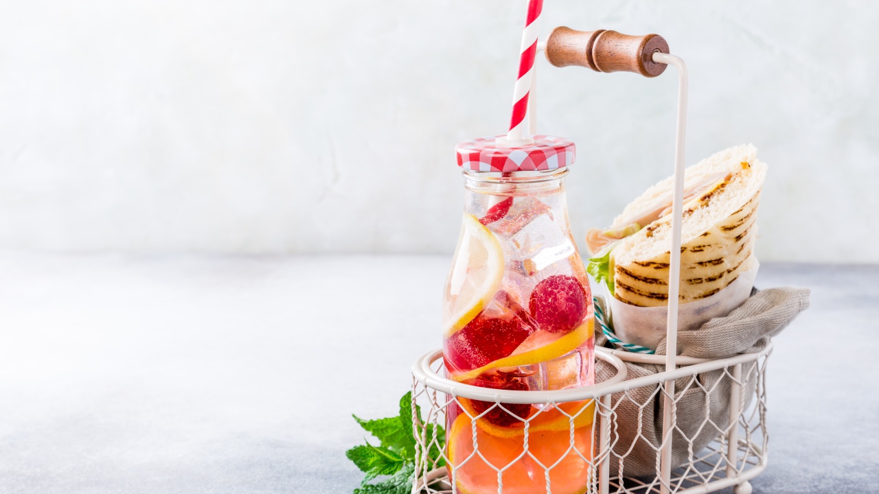 Банка с лимонадом в маленькой корзине с сэндвичем 