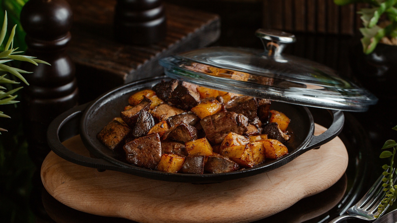 Печень с картофелем в сковороде на столе