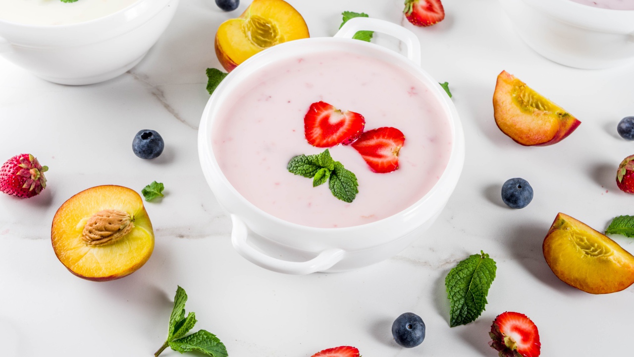 Молочный суп в тарелке на столе с ягодами и нектарином