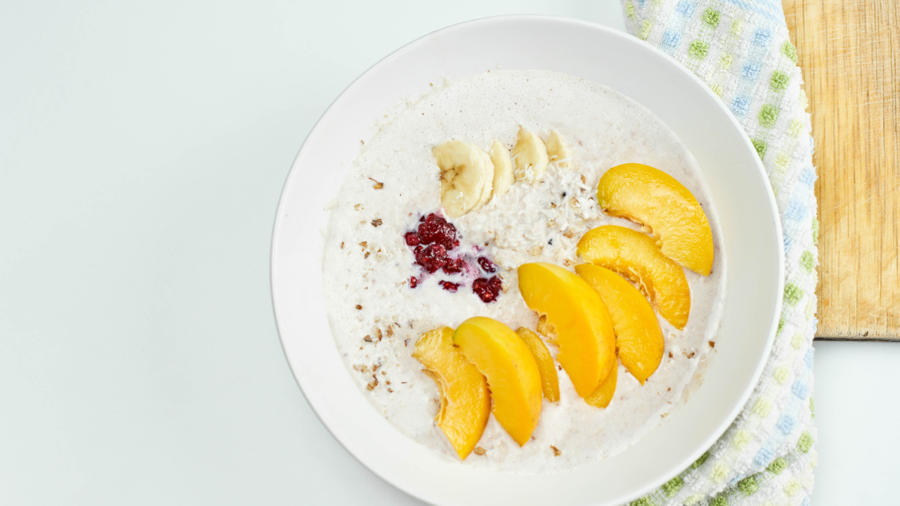 Мюсли с йогуртом в тарелке с кусочками банана и персика