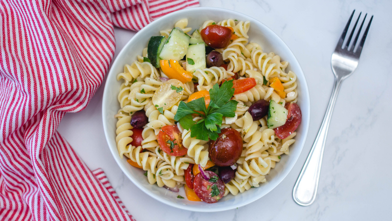 Макароны в тарелке с овощами на столе 