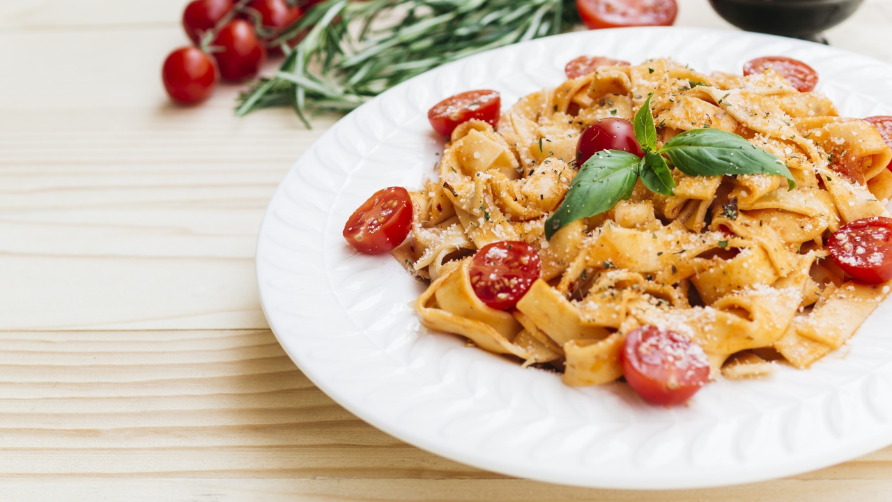 Паста с помидорами черри на белой тарелке