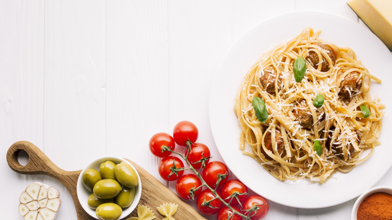 Паста с фрикадельками на столе с помидорами и оливками