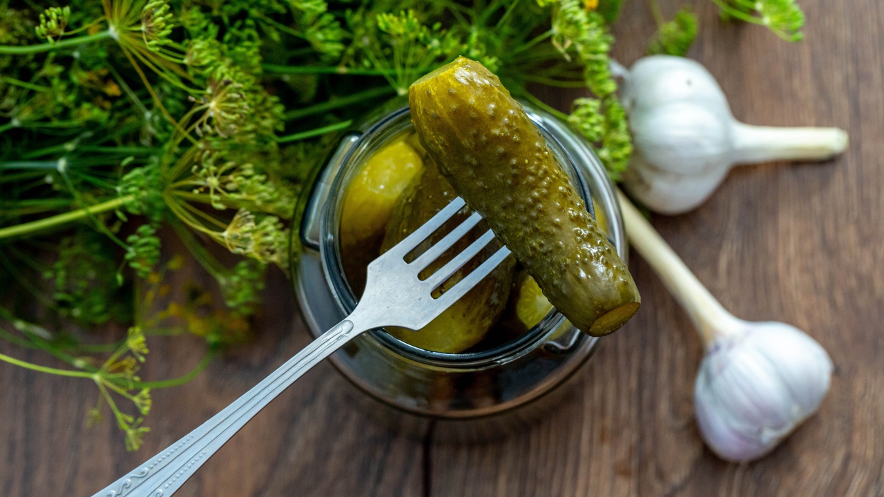 Маринованные огурцы в банке на столе с чесноком и укропом