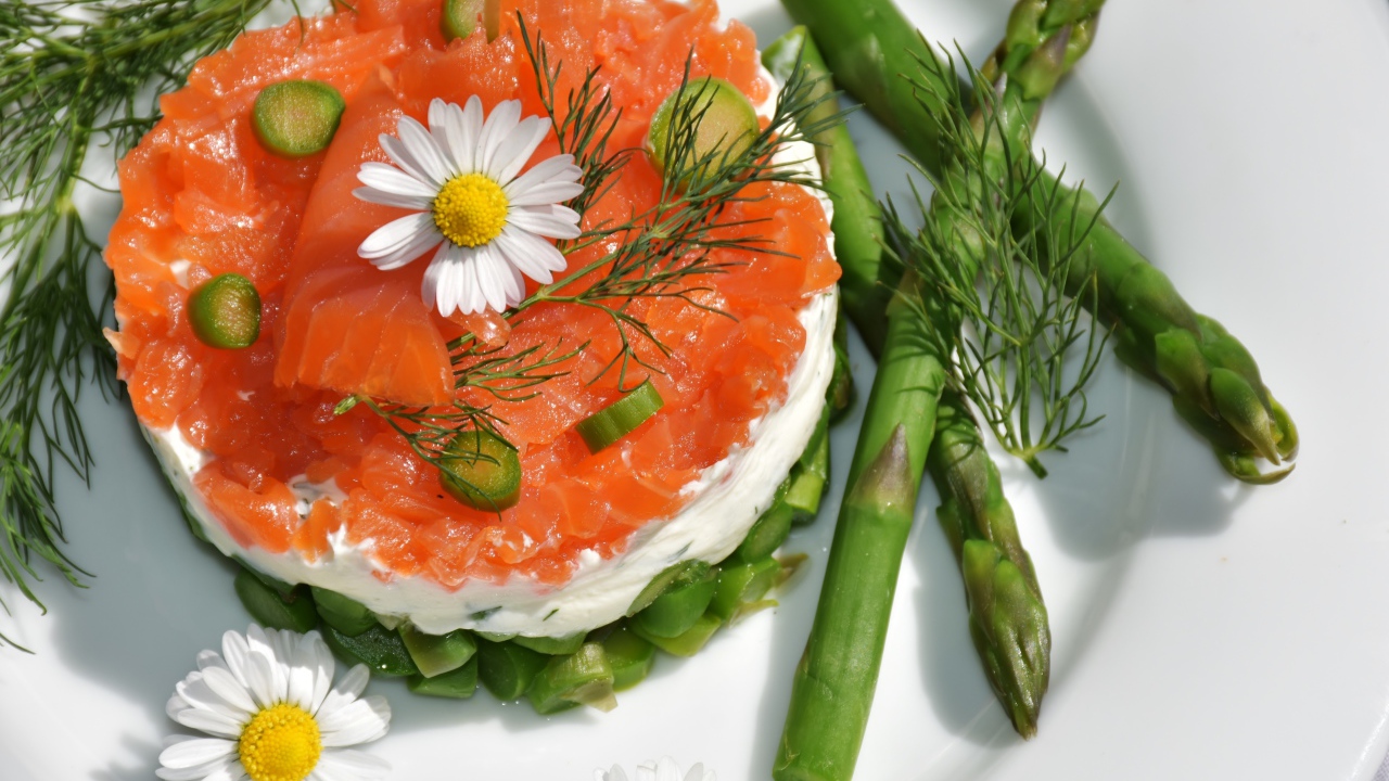 Red fish salad on a plate with asparagus, dill and chamomile flowers