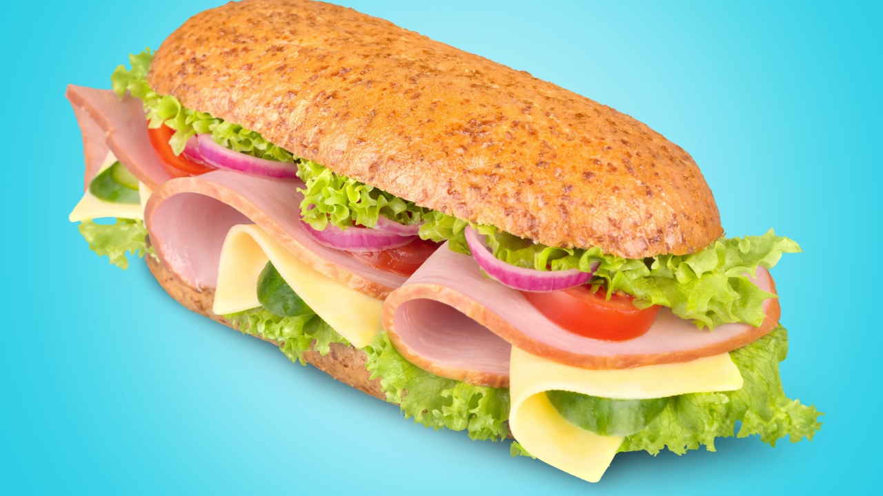 Бутерброд с ветчиной,сыром, помидорами луком и салатом на голубом фоне