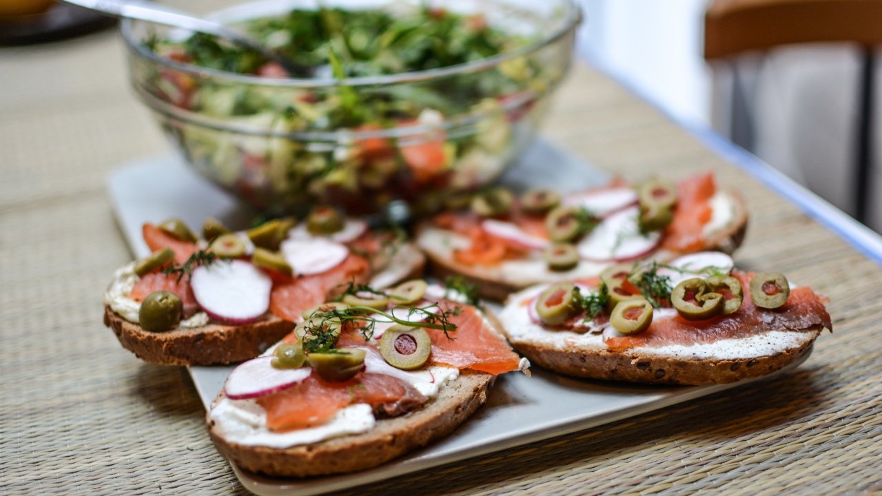 Бутерброды с маслом и красной рыбой на столе с салатом