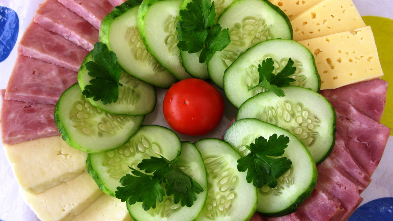 Сыр нарезанный, огурцы и ветчина на тарелке 