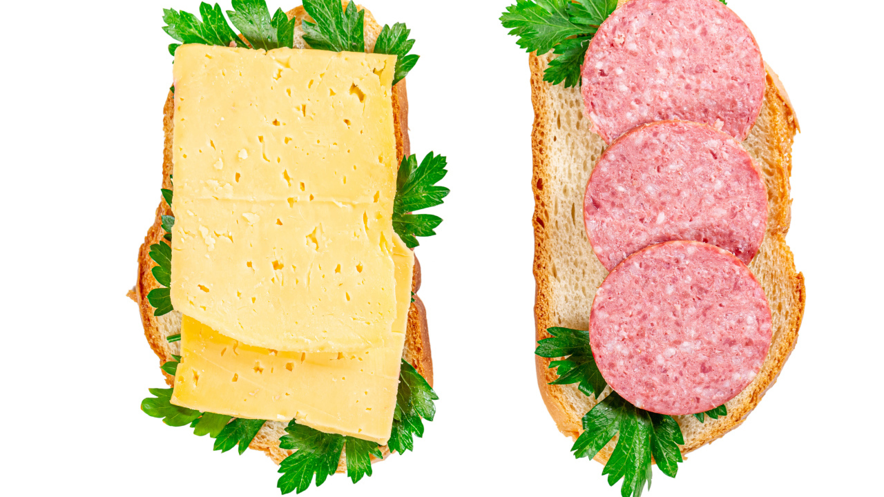 Two sandwiches with cheese, sausage, parsley on a white plate