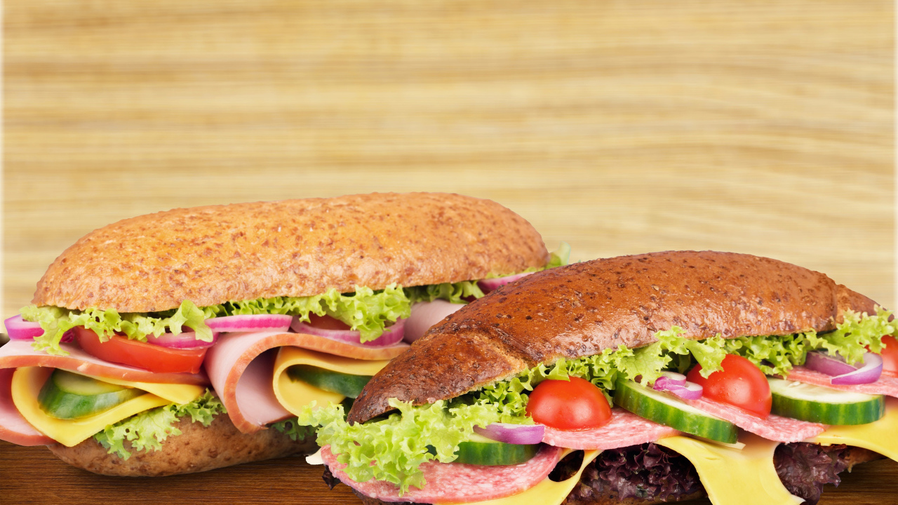 Два вкусных бутерброда с овощами и колбасой на столе 