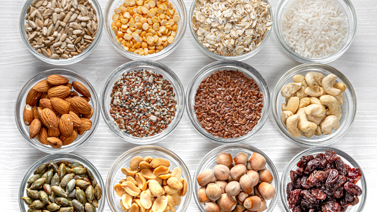 Разные виды орехов, круп и зерен в тарелках вид сверху 