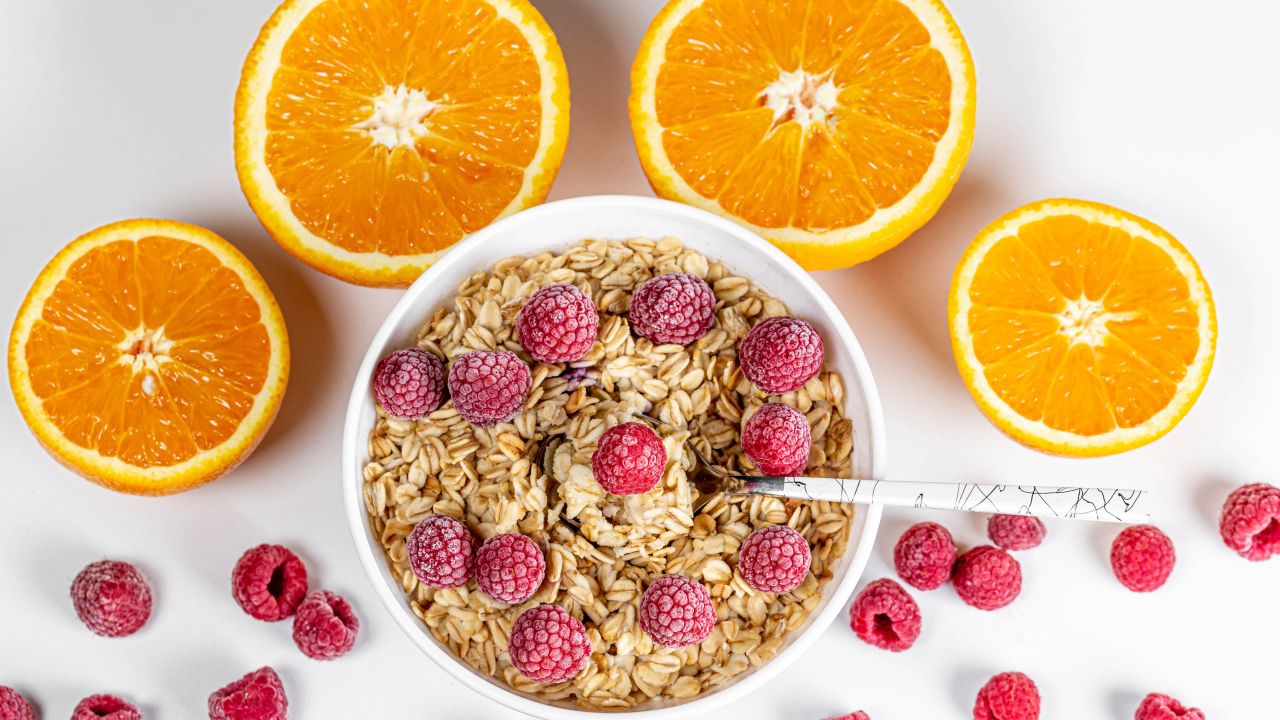 Овсяные хлопья с малиной на белом фоне с апельсинами