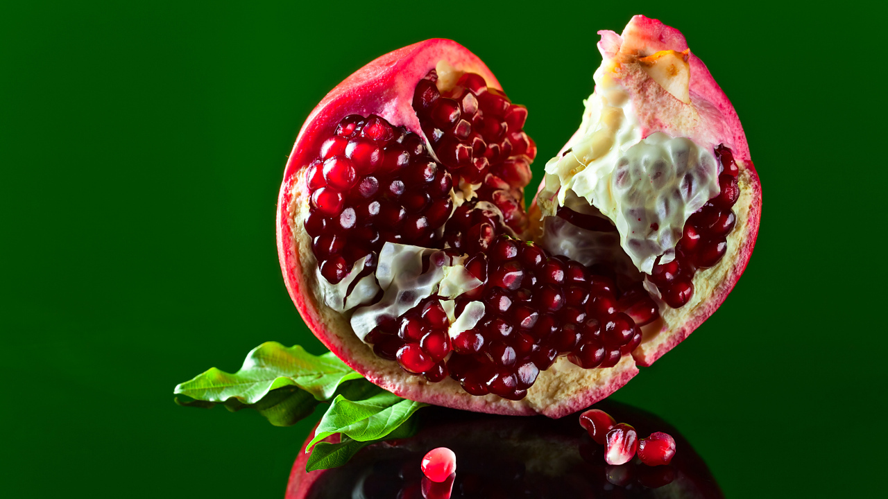Очищенный гранат на зеленом фоне